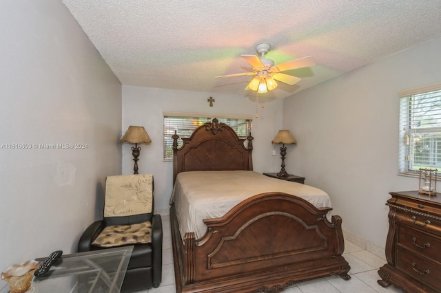 bedroom with a textured ceiling, light tile patterned floors, and ceiling fan