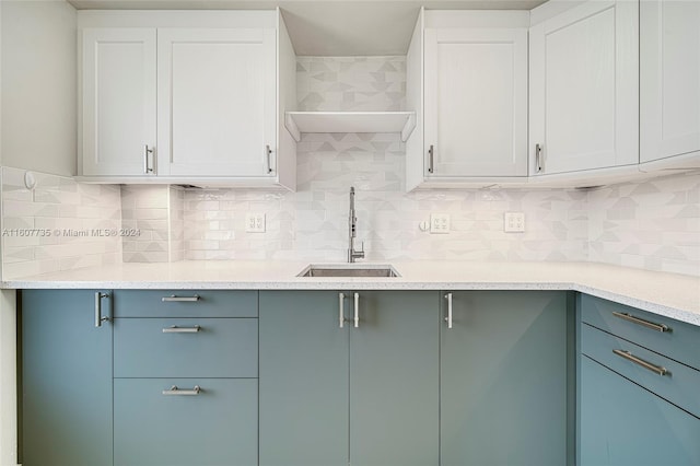 kitchen featuring sink, white cabinetry, tasteful backsplash, and light stone countertops