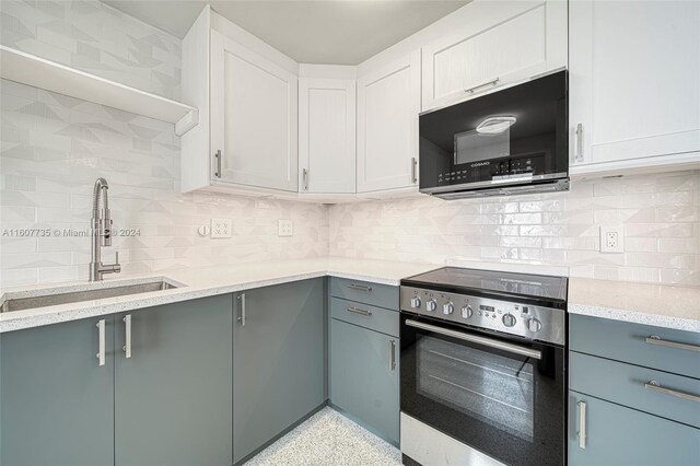 kitchen featuring tasteful backsplash, white cabinets, sink, light stone countertops, and electric range