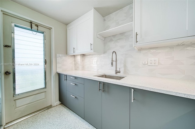 kitchen featuring sink, white cabinets, backsplash, and light stone countertops