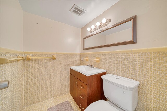 bathroom featuring tile walls, backsplash, toilet, and vanity