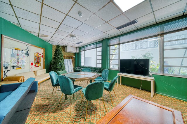 dining area with a drop ceiling, carpet, and plenty of natural light