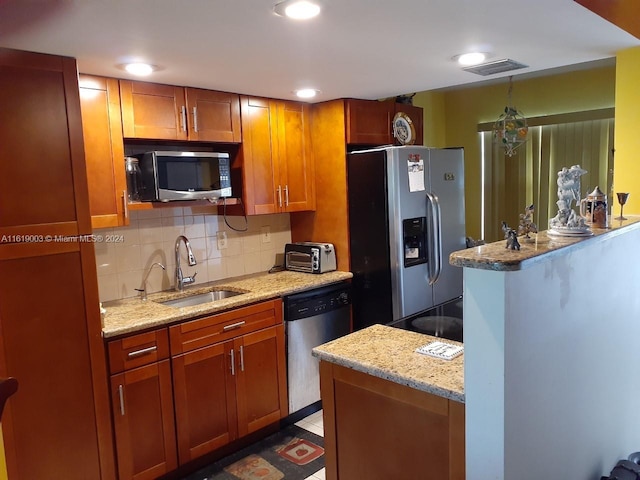 kitchen with sink, decorative light fixtures, appliances with stainless steel finishes, a notable chandelier, and light stone counters