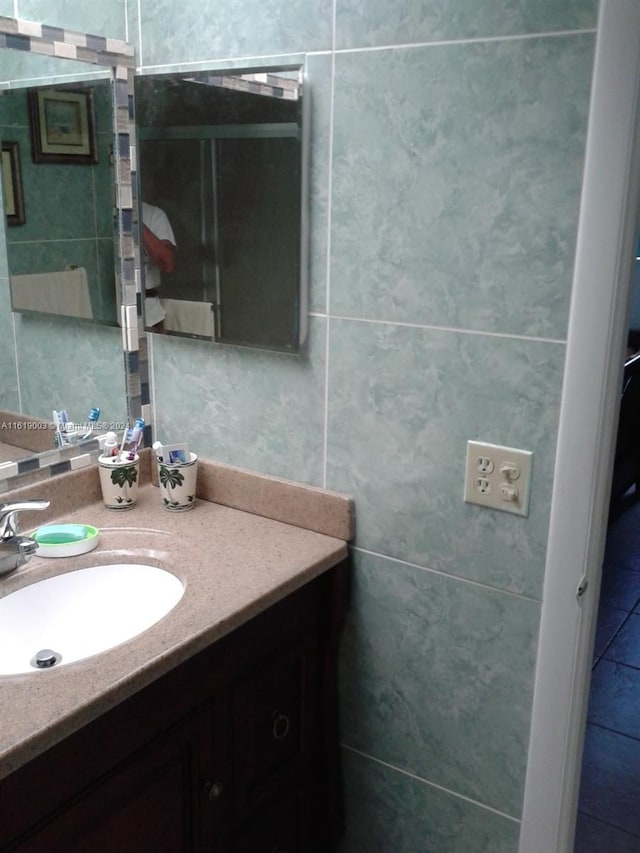 bathroom featuring vanity and tile walls