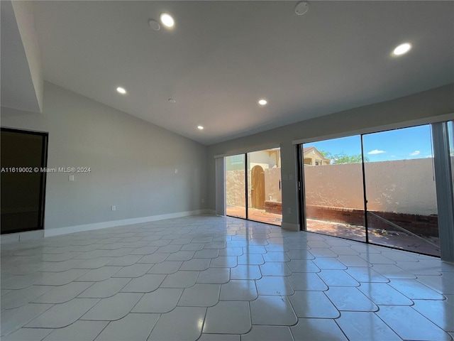 spare room featuring lofted ceiling and tile patterned flooring