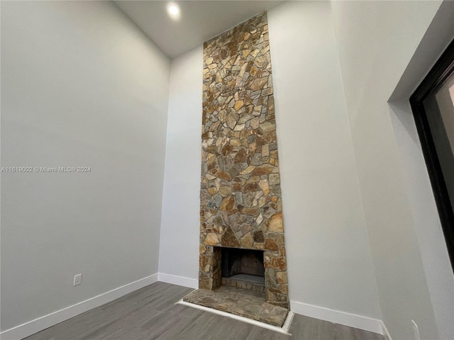 unfurnished living room featuring a stone fireplace and dark hardwood / wood-style floors