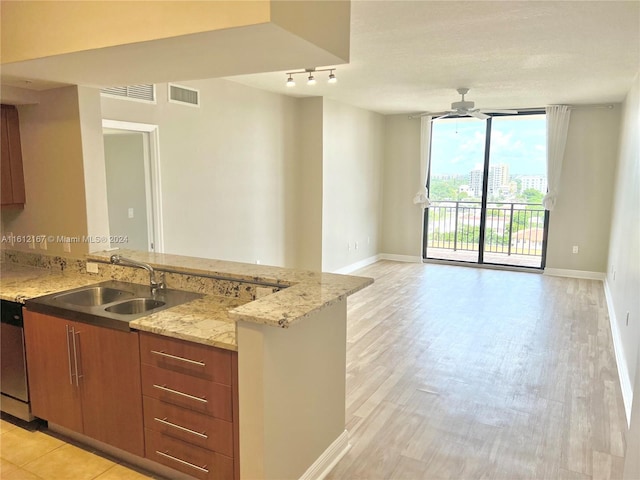 kitchen featuring sink, kitchen peninsula, stainless steel dishwasher, light hardwood / wood-style flooring, and light stone countertops