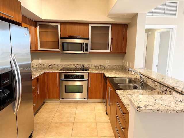 kitchen with light stone counters, light tile patterned floors, sink, kitchen peninsula, and stainless steel appliances