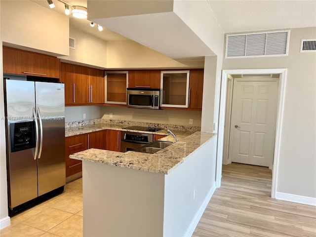 kitchen featuring light wood-type flooring, sink, kitchen peninsula, stainless steel appliances, and light stone countertops