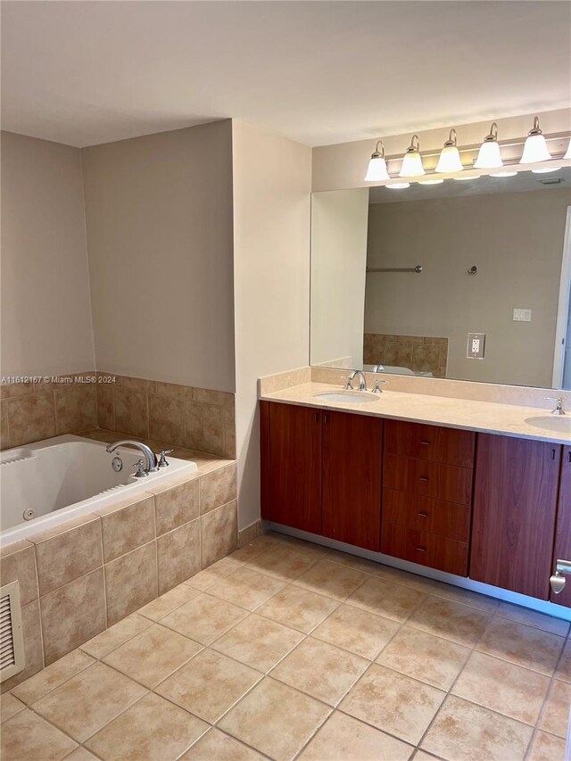 bathroom featuring tiled tub, vanity, and tile patterned flooring