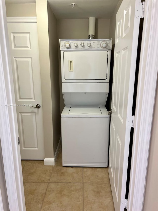 laundry area featuring stacked washer / drying machine and light tile patterned floors