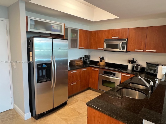 kitchen featuring sink, dark stone counters, and appliances with stainless steel finishes