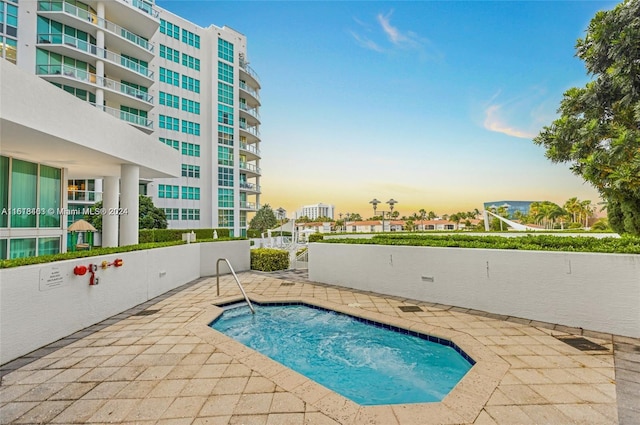 pool at dusk with a patio area