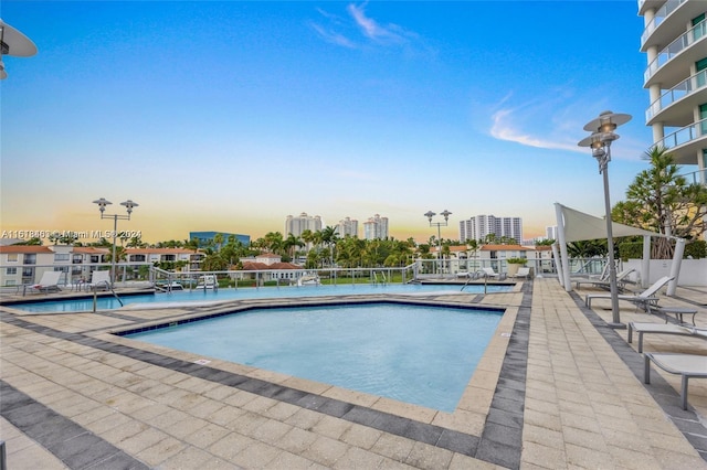 pool at dusk featuring a patio area