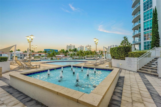 pool at dusk featuring a patio