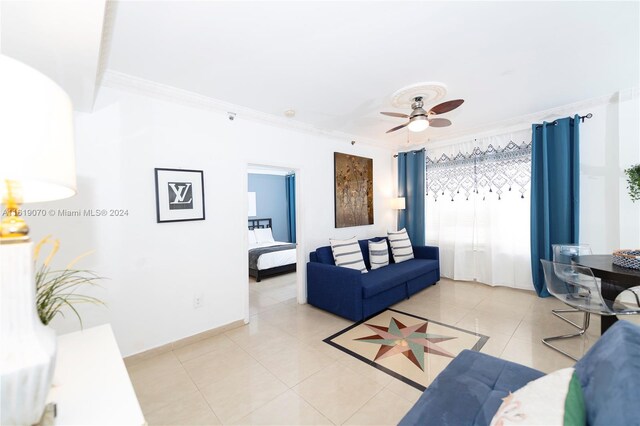 tiled living room with ceiling fan and ornamental molding