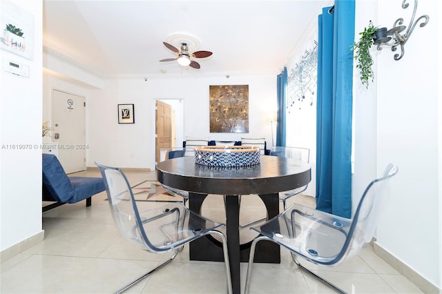 tiled dining area with ceiling fan and crown molding