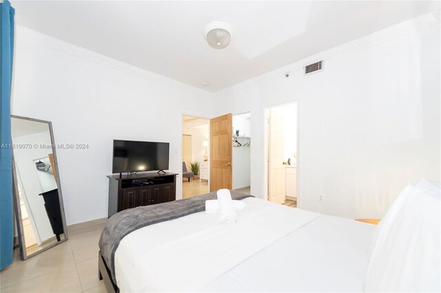 tiled bedroom with ensuite bath and crown molding