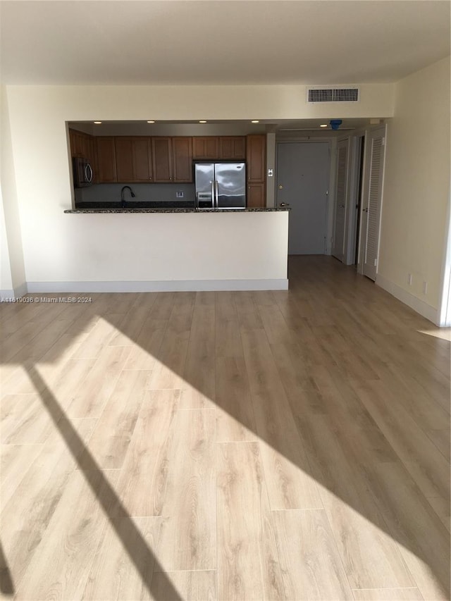 unfurnished living room with sink and light hardwood / wood-style floors