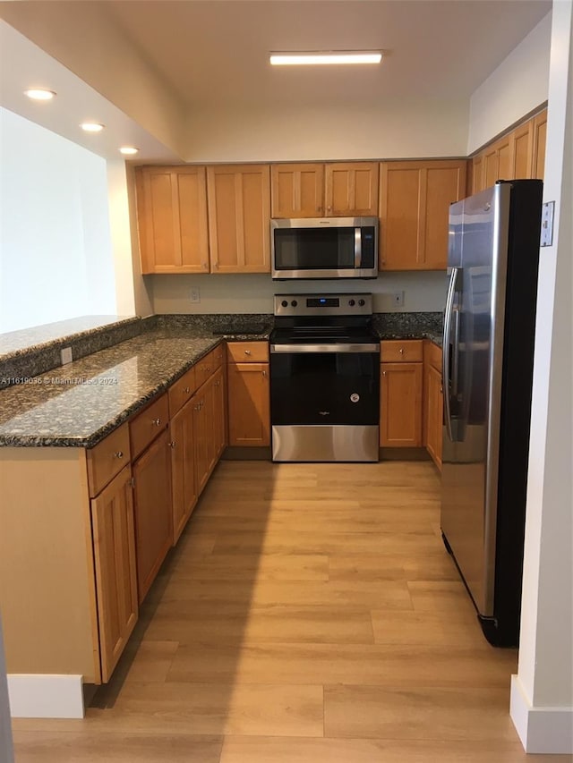 kitchen with dark stone counters, light hardwood / wood-style flooring, and appliances with stainless steel finishes