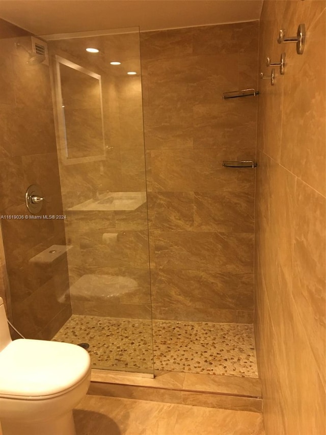 bathroom featuring tiled shower and toilet