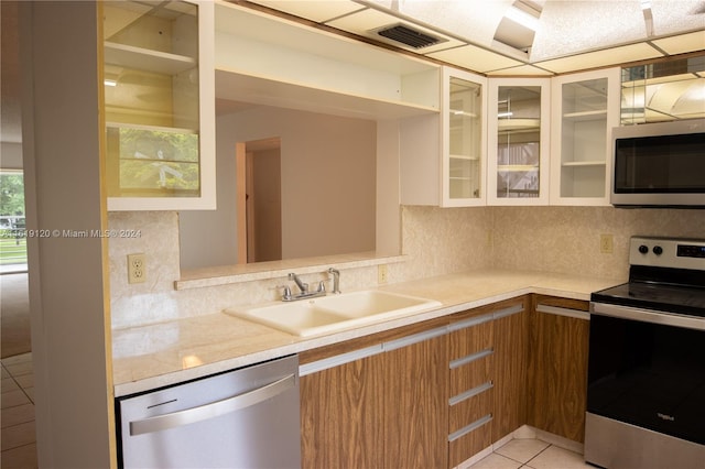 kitchen with sink, tasteful backsplash, light tile patterned floors, and appliances with stainless steel finishes