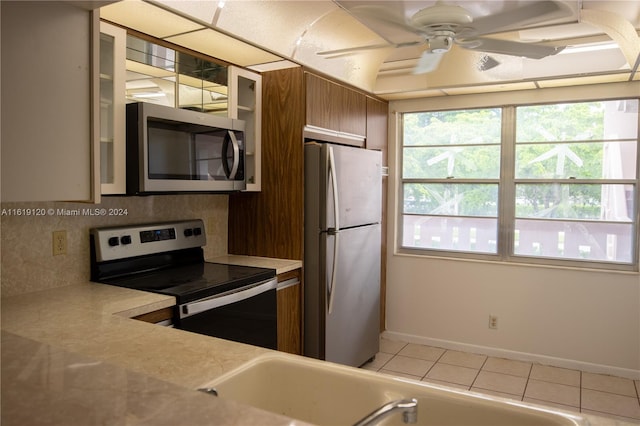 kitchen with ceiling fan, light tile patterned floors, appliances with stainless steel finishes, and decorative backsplash