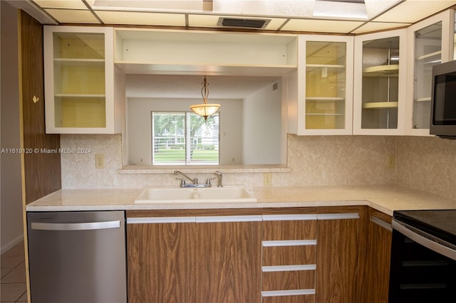 kitchen with appliances with stainless steel finishes, decorative backsplash, tile patterned flooring, sink, and pendant lighting