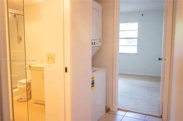 washroom with a textured ceiling, light carpet, and stacked washer and dryer