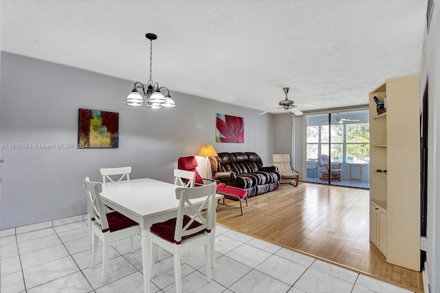 tiled dining area featuring ceiling fan with notable chandelier