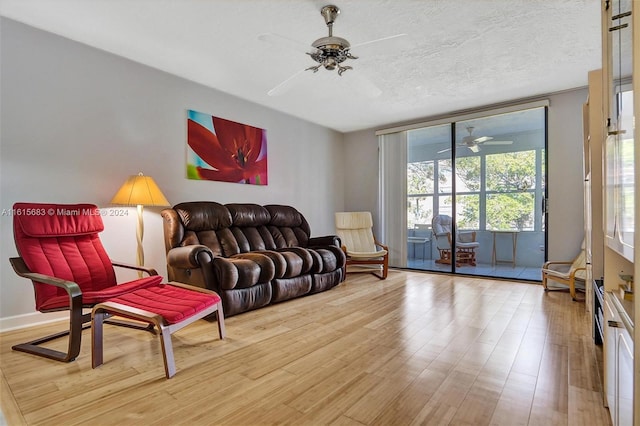 living room with a textured ceiling, ceiling fan, and light hardwood / wood-style floors