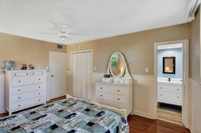 bedroom with dark hardwood / wood-style flooring, a closet, ensuite bath, and ceiling fan