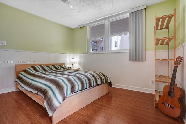 bedroom featuring a textured ceiling, ceiling fan, and dark hardwood / wood-style floors