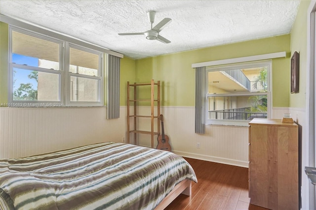 bedroom featuring ceiling fan, a textured ceiling, and dark hardwood / wood-style flooring