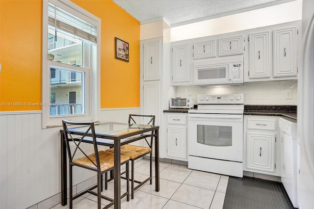 kitchen featuring a textured ceiling, tasteful backsplash, white appliances, and light tile patterned floors