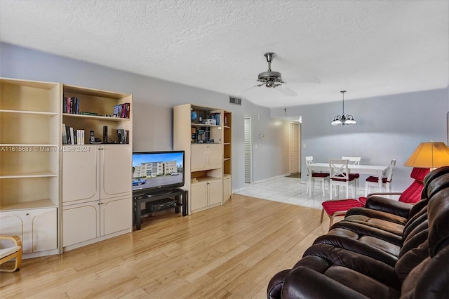 living room with ceiling fan, light wood-type flooring, and a textured ceiling