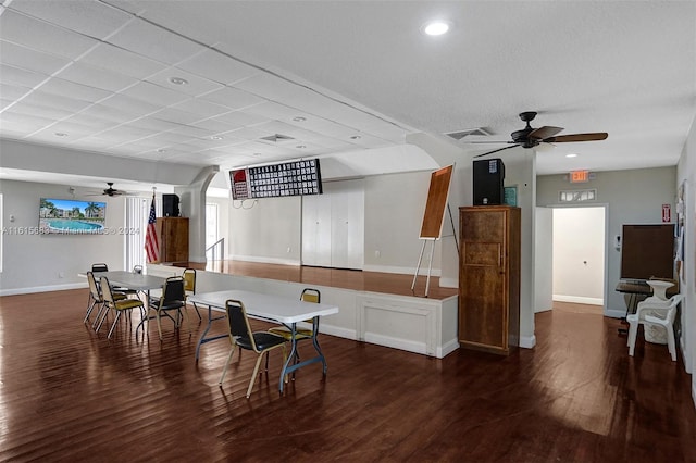 interior space with dark wood-type flooring, a drop ceiling, and ceiling fan