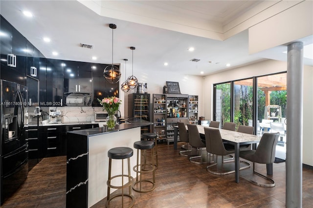 kitchen featuring a kitchen breakfast bar, pendant lighting, tasteful backsplash, a center island, and black fridge with ice dispenser