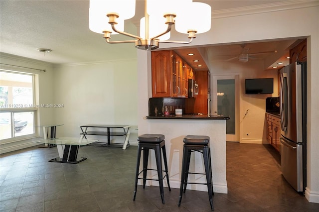 kitchen featuring crown molding, stainless steel fridge, a breakfast bar area, an inviting chandelier, and kitchen peninsula