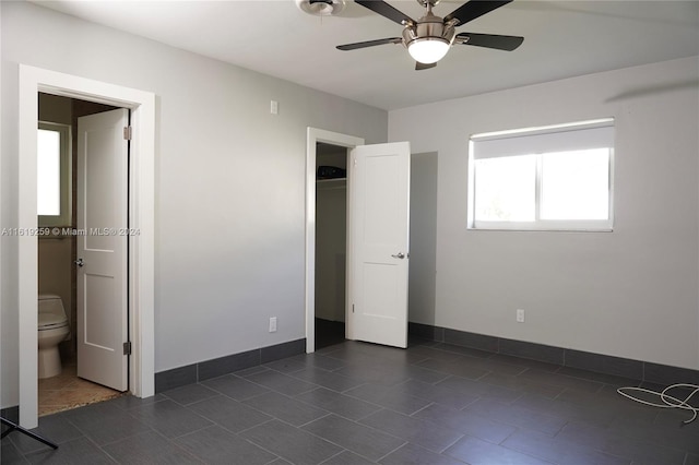 unfurnished bedroom with ceiling fan, ensuite bathroom, and dark tile patterned floors