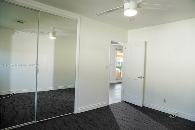 unfurnished bedroom featuring dark colored carpet, ceiling fan, and a closet