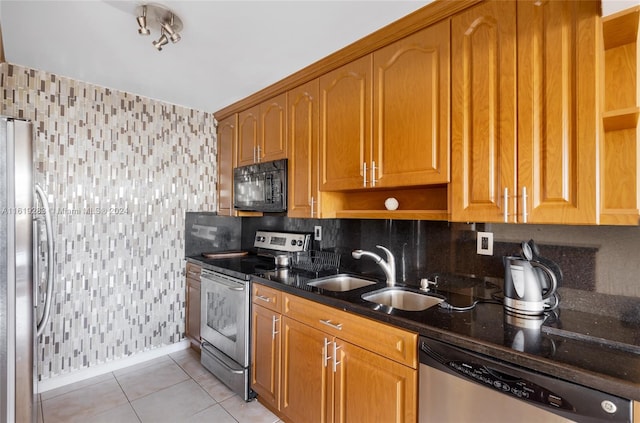 kitchen featuring dark stone counters, light tile patterned flooring, tasteful backsplash, sink, and appliances with stainless steel finishes