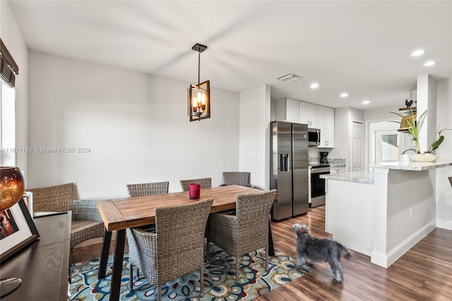 dining space featuring dark wood-type flooring and a notable chandelier