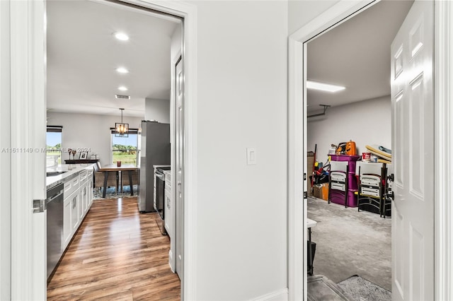 hallway with light hardwood / wood-style floors and a chandelier