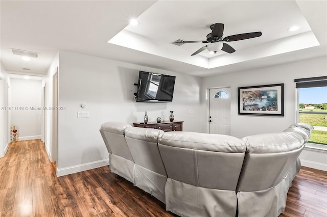 living room featuring ceiling fan, dark hardwood / wood-style flooring, and a tray ceiling