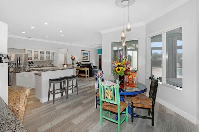 dining room with light wood-type flooring and ornamental molding