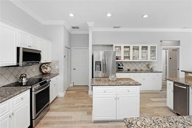 kitchen featuring light wood-type flooring, dark stone counters, white cabinetry, and stainless steel appliances