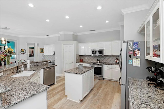 kitchen featuring stainless steel appliances, light wood-type flooring, sink, and a kitchen island