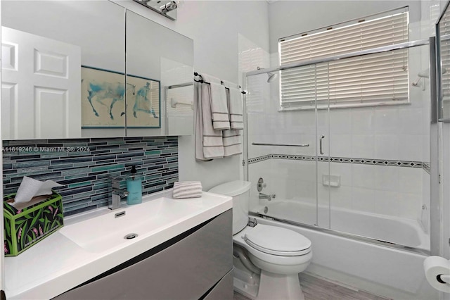 full bathroom with hardwood / wood-style flooring, combined bath / shower with glass door, backsplash, vanity, and toilet