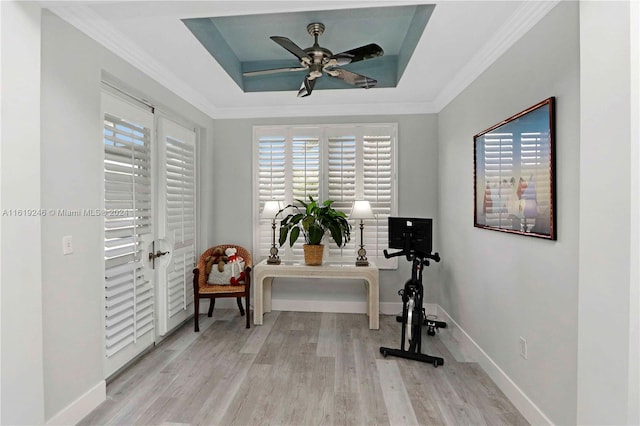 workout room with crown molding, a tray ceiling, ceiling fan, and light hardwood / wood-style flooring